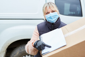 Parcel carrier with face mask asks for signature for confirmation