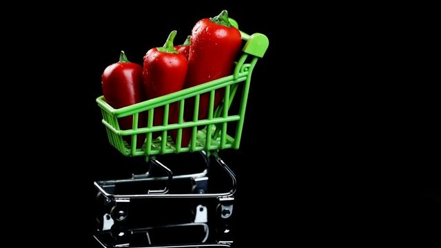 shopping concept. mini red pepper in a shopping cart rotating on a dark background.