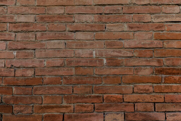 Fototapeta premium Beautiful brick wall with colorful red brown bricks uneven and cracked with space for texture background
