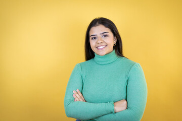 Young caucasian woman over isolated yellow background with a happy face standing and smiling with a confident smile showing teeth with arms crossed