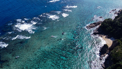 青い海に白波が立つサンゴ礁とビーチの俯瞰写真