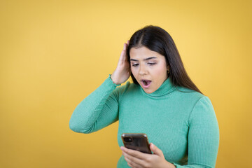 Young caucasian woman over isolated yellow background chatting on the phone with a worried expression