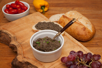 A tapenade served on a platter with fresh veg, grapes and a loaf of sourdough