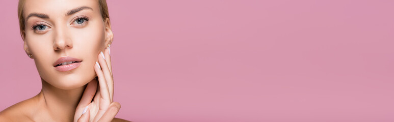 Obraz premium beautiful blonde woman with perfect skin touching face isolated on pink, banner