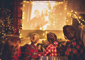 family mother father and children watching projector, TV, movies with popcorn in   christmas evening   at home.