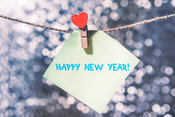 New year greeting card. The sticker hangs on the background of new year's bokeh. The inscription on the sticker happy new year.