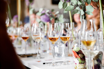 Tasting strong alcoholic drinks from beautiful glasses in a well-lit room with fresh flowers