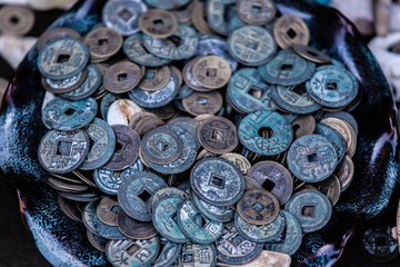 A plate full of oxidized old Chinese coins with square holes in them (they were used from used from...