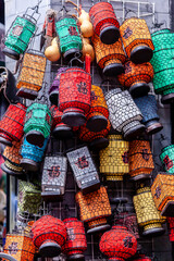 A wall full of colorful lanterns on a Chinese flea market, hanging on metal rails, waiting to be bought.