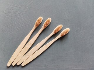 A family set of four wooden toothbrushes on grey background