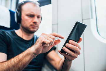 Personal gadget in the hand of a man traveling by train - online cinema and music - reading an e-book