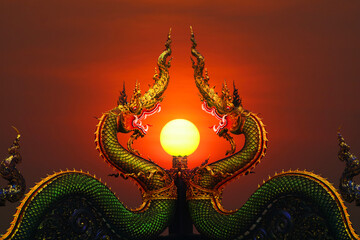 Two Naga status and pole in middle and sunset red sky on top of pole clear evening cloud - obrazy, fototapety, plakaty