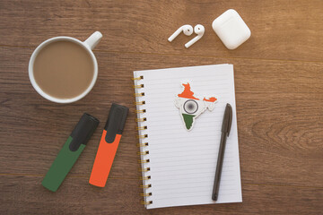notepad with india flag, wireless headphones, coffee cup, pen, markers on brown table, study concept 
