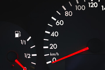 Black dial of car instruments with white arrows - fuel gauge and speedometer on the dashboard