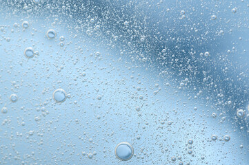 The texture of a transparent cosmetic gel with bubbles on a blue background. Serum, moisturizing...