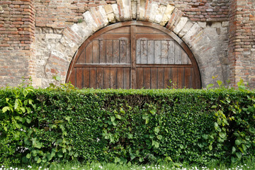 Fototapeta na wymiar Brick fortress wall with wooden gates and green sheared bushes, Belgrade, Serbia.