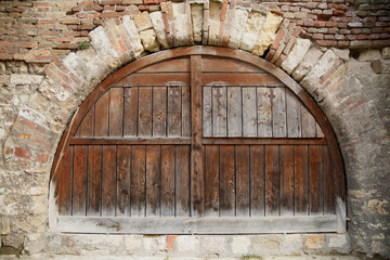Wooden ancient gate in the arch in the fortress wall of brickwork.