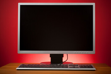 Silver computer screen and keyboard. Studio photo isolated on red background. 
