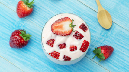 Strawberry yogurt on a blue wooden table.