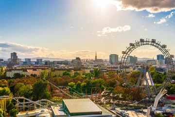 Papier Peint photo autocollant Vienne City view of Vienna, Austria, from above at Prater amusement park. Iconic fairy wheel and other amusement rides in the background with the sun peeking out of the clouds.