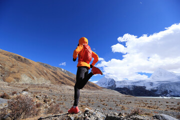 Woman trail runner cross country running in high altitude winter nature