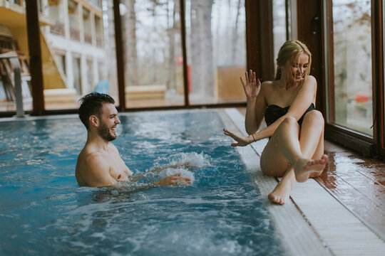 Young couple relaxing on the poolside of interior swimming pool