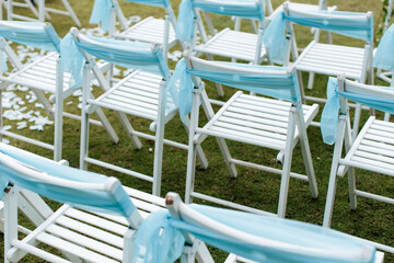 Fototapeta na wymiar View of white chairs with blue ribbons in a wedding