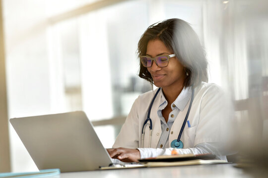 Woman Doctor Working In Office With Laptop Computer; Wearing Face Mask