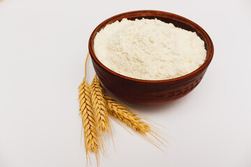 Wheat flour in bowl and spikelets isolated on white