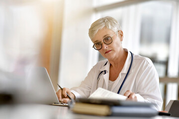 Mature female practitioner working on laptop computer