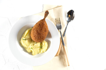 Chicken Kiev cutlet with mashed potatoes and slice on a plate, white background