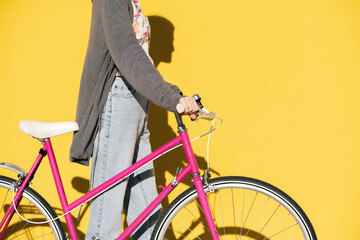 unrecognizable woman in a yellow wall with a bike