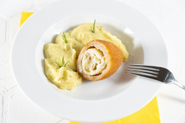 Chicken Kiev cutlet with mashed potatoes and slice on a plate, white background
