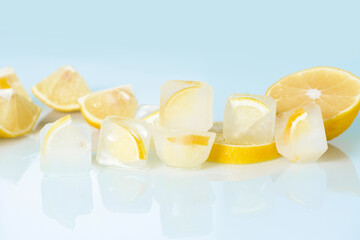 cosmetic ice cubes with lemon and vitamin C for skin care on a blue light background, natural organic ingredients for home care, detox. place for text