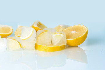 cosmetic ice cubes with lemon and vitamin C for skin care on a blue light background, natural organic ingredients for home care, detox. place for text