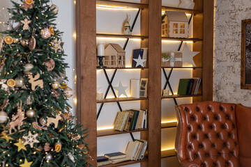 Fototapeta na wymiar christmas interior with armchair, against the background of the bookshelf. Home and cozy atmosphere with a Christmas tree