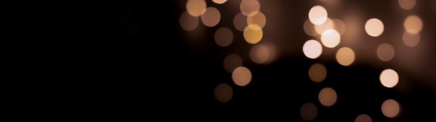 Beautiful festive bokeh on a black background golden circles, light night bokeh effect, deflated. Festive postcard, night view.