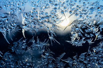 Delicate Texture of ice pattern and frozen water drops on a window pane as a natural Christmas greeting card. Sunset and Navy Blue Gradiented Background. Macro shoot with shallow depth of field.