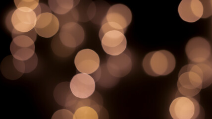 Beautiful festive bokeh on a black background golden circles, light night bokeh effect, deflated. Festive postcard, night view.