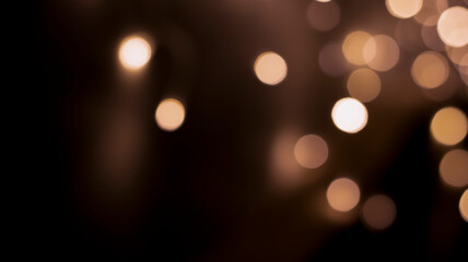 Beautiful festive bokeh on a black background golden circles, light night bokeh effect, deflated. Festive postcard, night view.