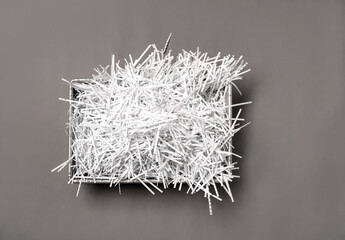 Shredded white paper are piled up in a metal box seen from above.