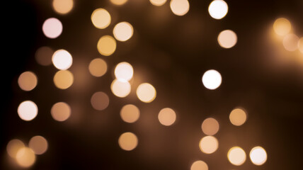 Beautiful festive bokeh on a black background golden circles, light night bokeh effect, deflated. Festive postcard, night view.