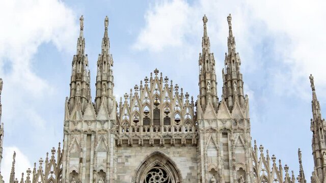Time lapse of Milan cathedral or duomo di milano during a sunny cloudy day. There is the gothic style church in close up and the clouds in background