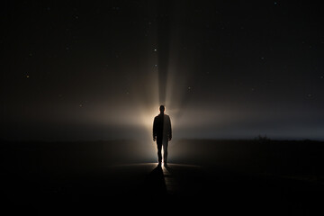 backlighting of a man in the dark of a foggy night and a light behind the model