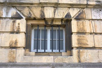 a barred window of a dirty stone wall 