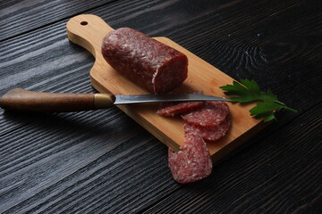 Raw smoked sausage sliced and nos on a wooden cutting board