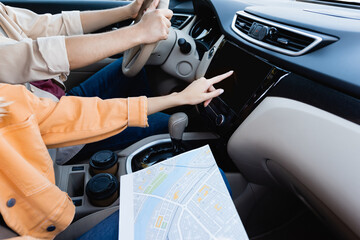Cropped view of woman with map using audio system while husband driving car