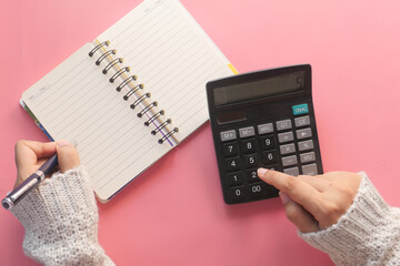 Women hand using calculator on pink background
