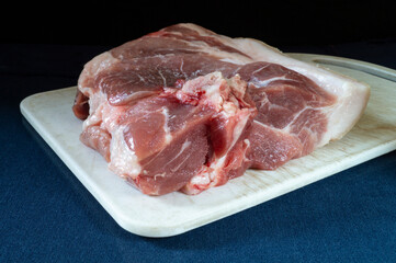 Piece of meat of the pork with white board on turn blue table