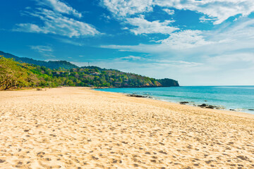 Tropical beach with white sand and green mountain near blue sea in Koh Lanta island, Thailand